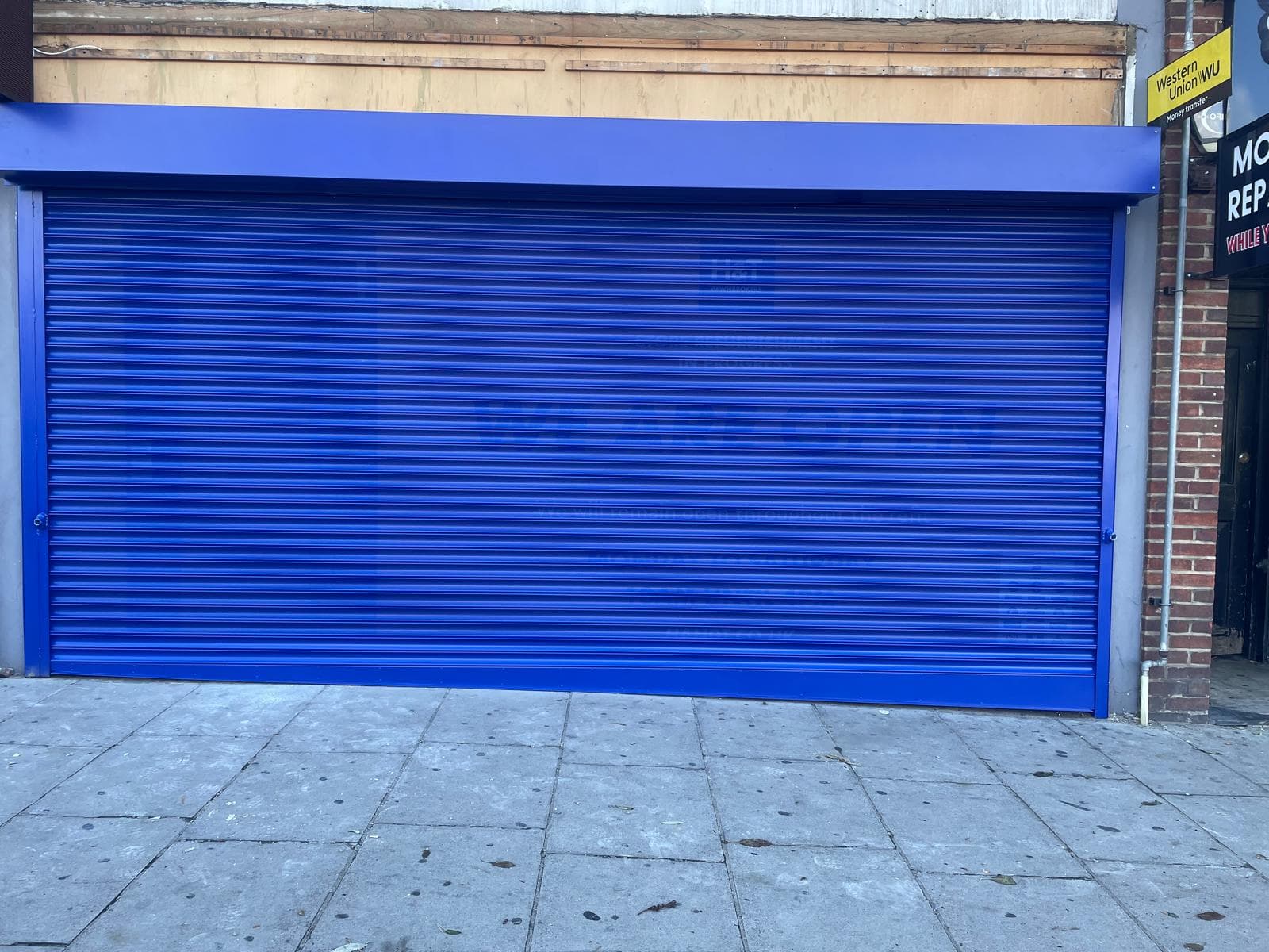 Perforated roller shutter installed above shopfront entrance